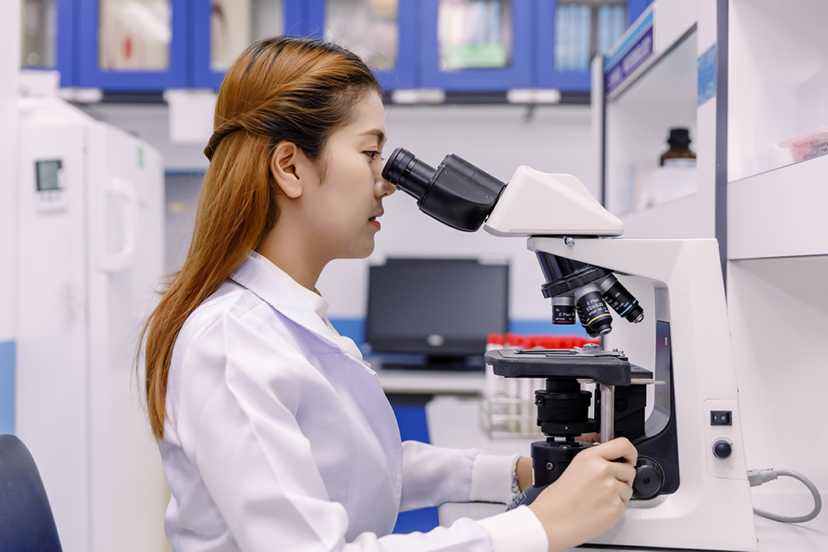 Woman behind a microscope: technology can benefit medical devices.