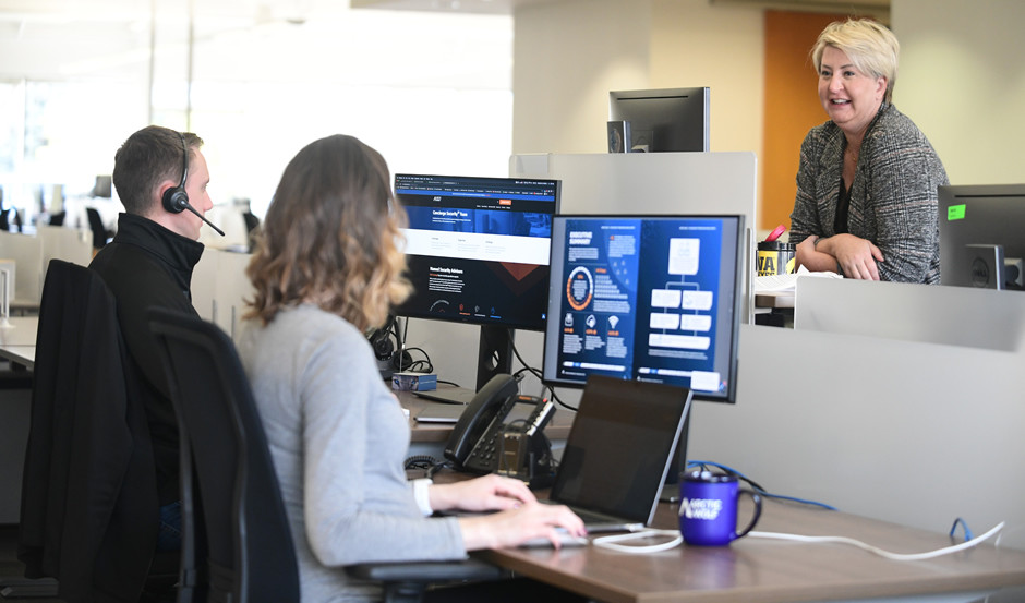 Two employees at their computers, both wearing headsets