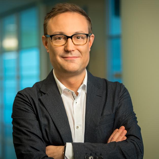 Dr. Christopher Arendt, Oncology Therapeutic Area Unit Head, Takeda wearing glasses a suit with no tie, with arms crossed.