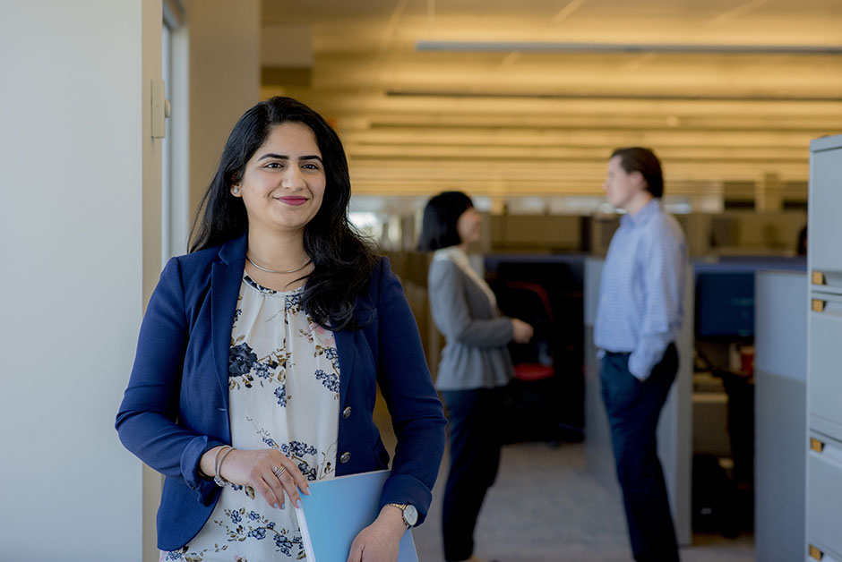 A young woman employee in the Citi office tower in Mississauga, Ontario. Behind her, two colleagues are convening.